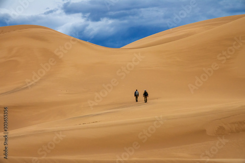 Two travelers in the desert. Hiking on sand dunes in mountains. Gobi desert, Mongolia
