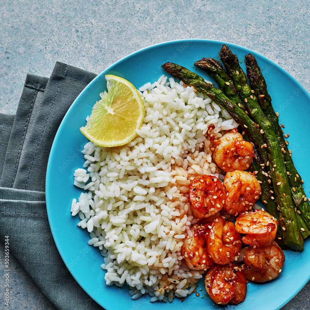 Φωτογραφία Teriyaki coated shrimps stir fry with grilled asparagus, basmati rice and sesame seeds served on a blue plate
