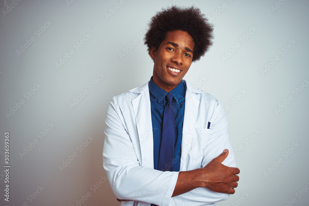 Young african american doctor man wearing coat standing over isolated white background happy face smiling with crossed arms looking at the camera. Positive person. Young african american doctor man wearing coat standing over isolated white background happy face smiling with crossed arms looking at the camera. Positive person.