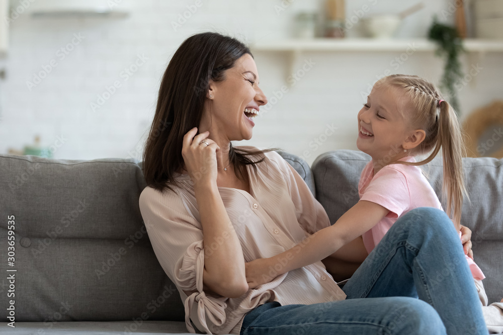 Overjoyed small girl tickling laughing 30s mommy. Overjoyed small girl tickling laughing 30s mommy.