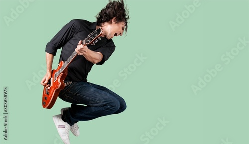 Male Guitarist playing music on grey wall photo