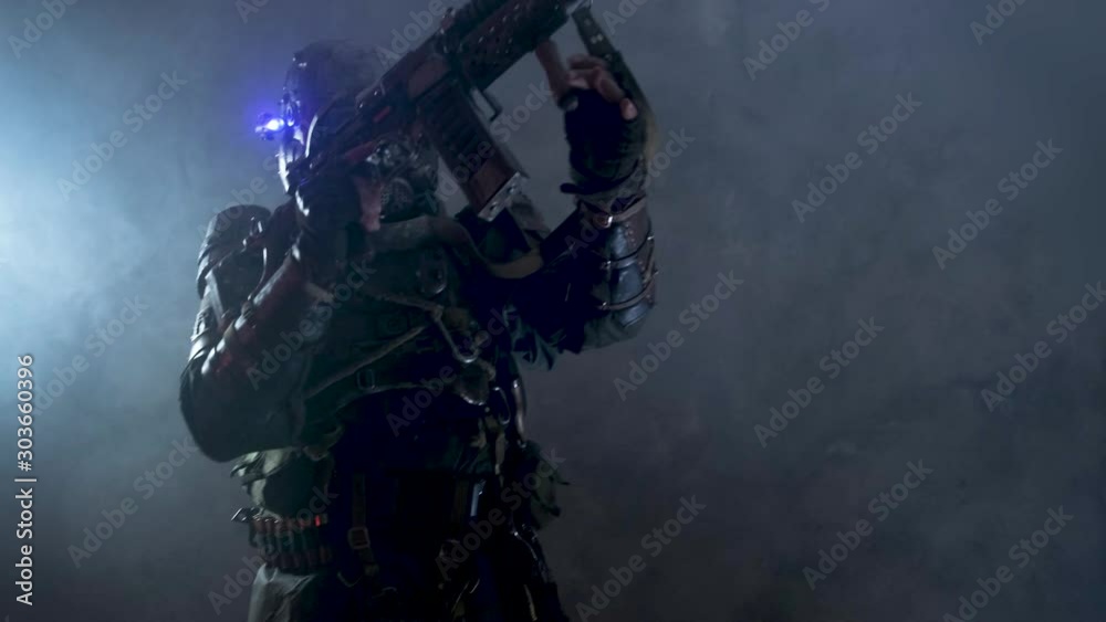 Post apocalypse soldier is aiming from his weapon, while posing for camer man in mist and smoke. Post apocalypse soldier is aiming from his weapon, while posing for camer man in mist and smoke.
