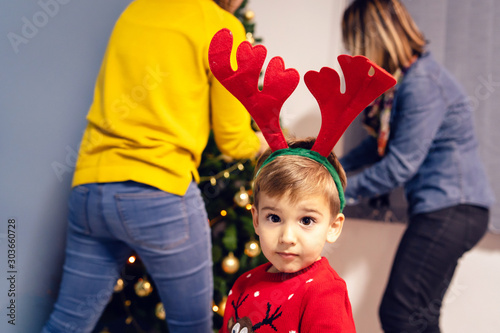 Fotografie Small boy two or three years old in front of the christmas tree decorating for n