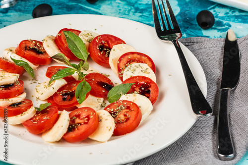 Caprese salad. Healthy meal with cherry tomatoes, mozzarella balls, spices, fresh rocket and basil. Home made, tasty food. Symbolic image. Concept for a tasty and healthy vegetarian meal. Close up.