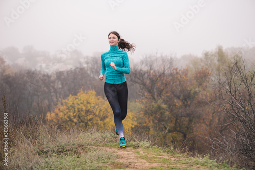 Pretty woman jogging in autumn morning forest