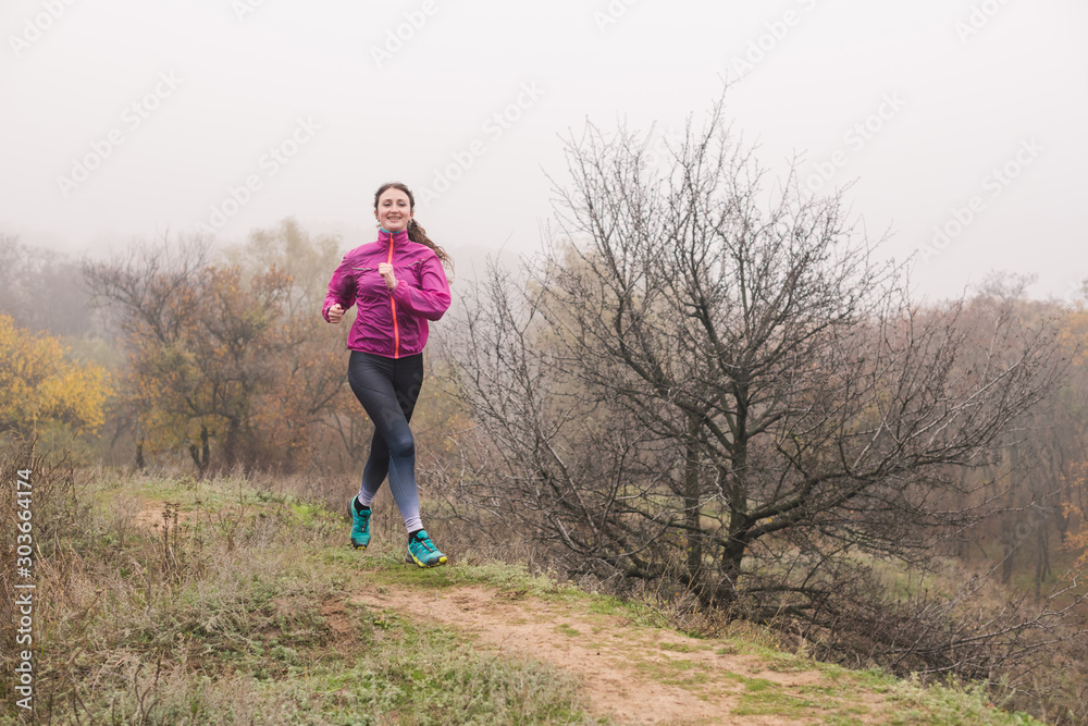 Pretty woman jogging in autumn morning forest