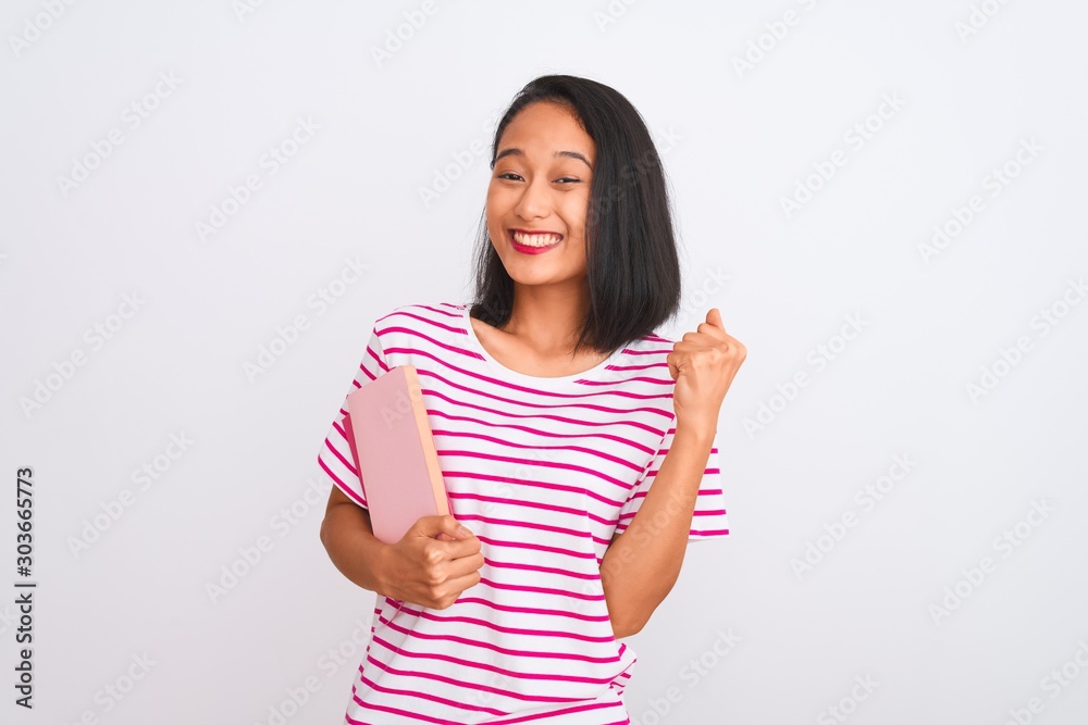 Young beautiful chinese woman holding books standing over isolated white background screaming proud and celebrating victory and success very excited, cheering emotion Young beautiful chinese woman holding books standing over isolated white background screaming proud and celebrating victory and success very excited, cheering emotion