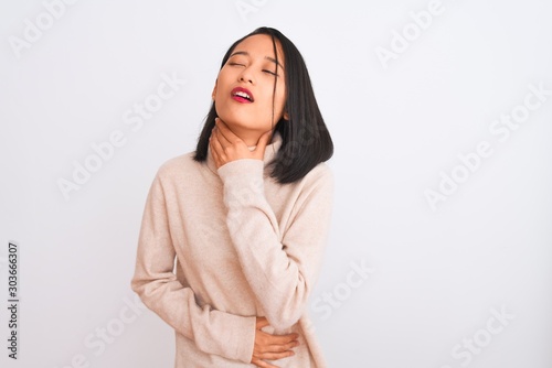 Young chinese woman wearing turtleneck sweater standing over isolated white background Touching painful neck, sore throat for flu, clod and infection © Krakenimages.com