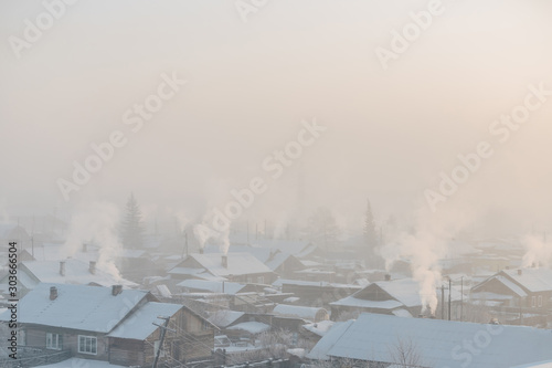 A cold winter day. It's frosty outside. Village houses with chimney smoke.