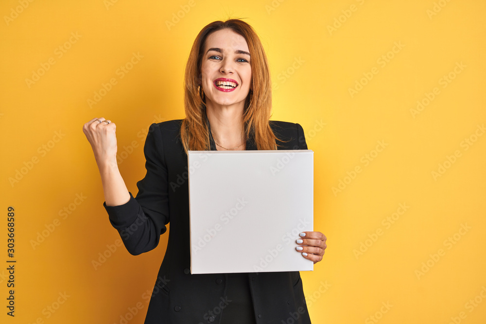 Young redhead businesswoman with clear eyes holding banner over isolated yellow background screaming proud and celebrating victory and success very excited, cheering emotion Young redhead businesswoman with clear eyes holding banner over isolated yellow background screaming proud and celebrating victory and success very excited, cheering emotion