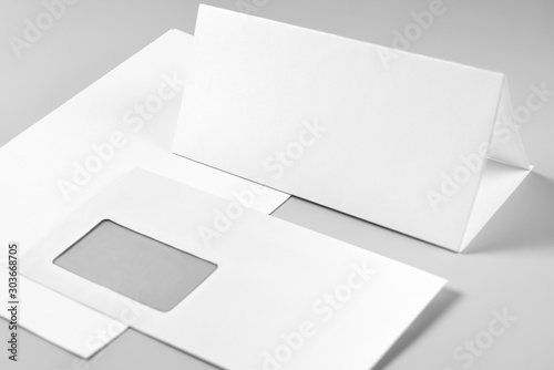 Blank Folded Sheet of Paper, Letterhead, or Flyer and Envelope over Stack of Paper