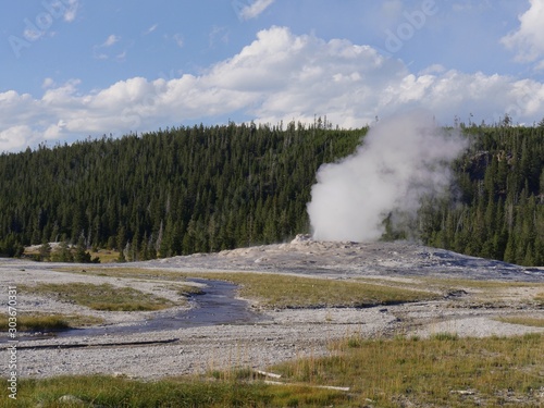 Scenic view of the Old Faithful Geyser with steam and scalding water spurting out in an early morning eruption at Yellowstone National Park.