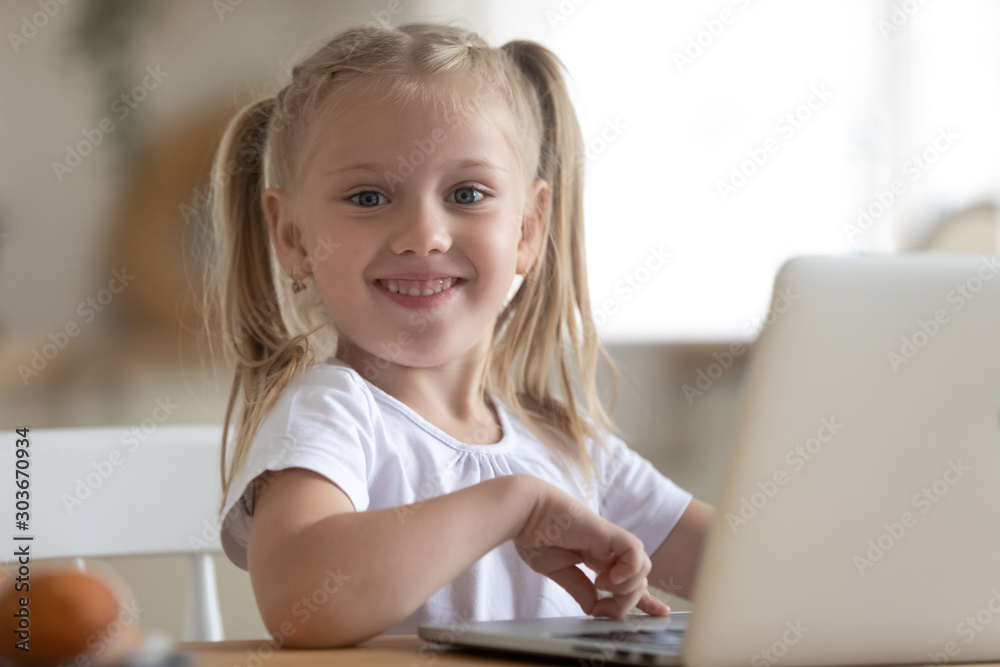 Happy little preschool kid sitting at table with computer. Happy little preschool kid sitting at table with computer.