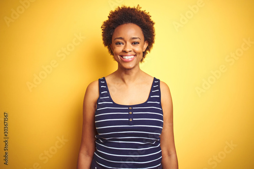Beauitul african american woman wearing summer t-shirt over isolated yellow background with a happy and cool smile on face. Lucky person.