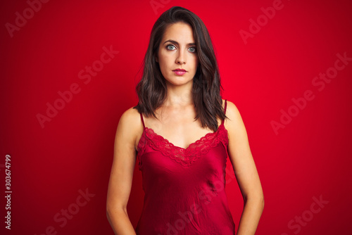 Young beautiful woman wearing sexy lingerie over red isolated background Relaxed with serious expression on face. Simple and natural looking at the camera.