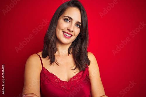 Young beautiful woman wearing sexy lingerie over red isolated background happy face smiling with crossed arms looking at the camera. Positive person.