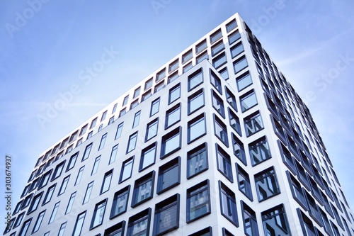 Modern European building. White building with many windows against the blue sky. Abstract architecture, fragment of modern urban geometry.