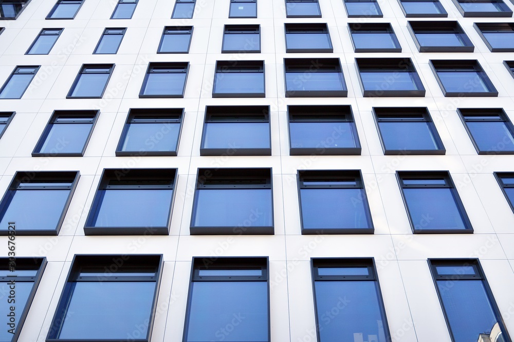 Modern European building. White building with many windows against the blue sky. Abstract architecture, fragment of modern urban geometry. Modern European building. White building with many windows against the blue sky. Abstract architecture, fragment of modern urban geometry.