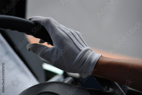 The arm and the hand of a  japanese bus driver in a white glove in a tourist bus in Nikko-Japan on the handlebar.