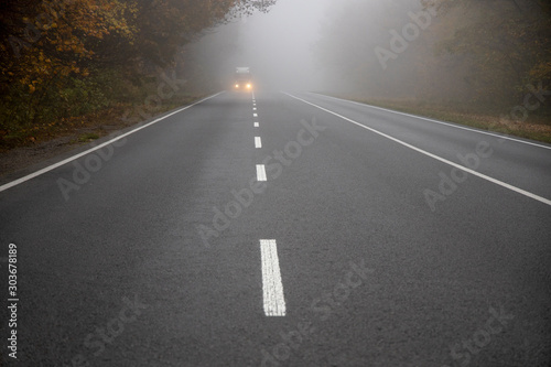 Car on the road in the fog. Autumn landscape. © Olivkairishka