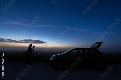 photographer with the car in the field, night, backlight