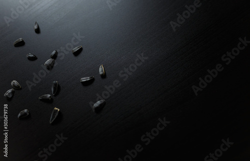 Obraz na plátně Sunflower seeds thrown around on black wooden table