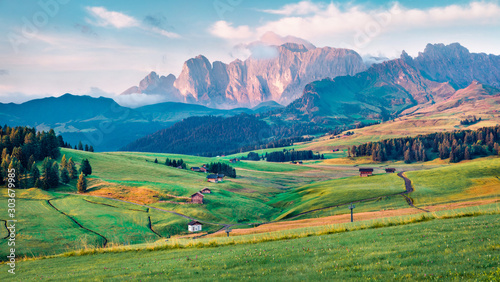Colorful morning scene of Compaccio village, Seiser Alm or Alpe di Siusi location, Bolzano province, Italy, Europe. Stunning summer view of Dolomiti Alps. Beauty of countryside concept background.