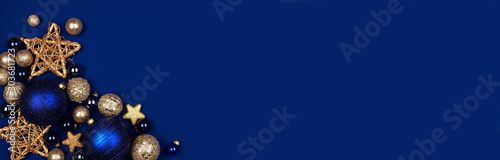 Christmas corner border banner of dark blue and gold ornaments. Overhead view on a midnight blue background. photo