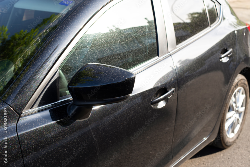 Black car is dirty parked on the street.