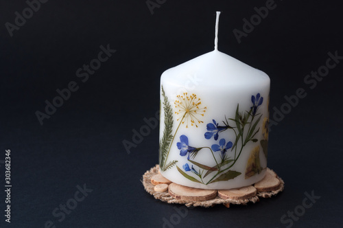 Candle with herbarium flowers. isolated on black background. photo