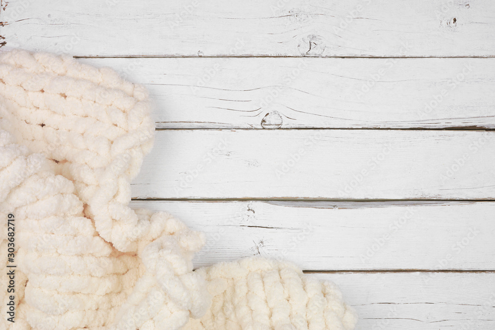 Cozy knitted thick wool blanket. Corner border top view on a white wood