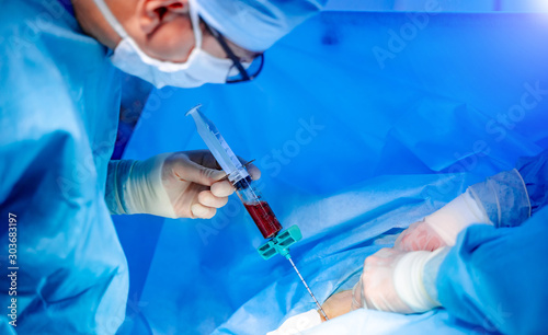 Bone marrow transplant operation. Surgeons in medical uniform and masks working in the operating room. photo