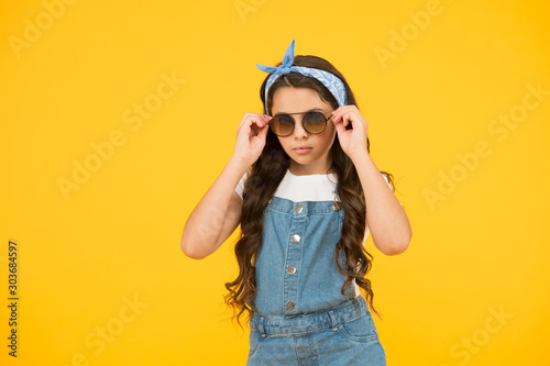 hot and sunny. cheerful little girl yellow wall. retro child long hair. small kid vintage sunglasses. Vacation mode on. Little fashionista. Kids clothes boutique. retro girl. Summer fashion concept