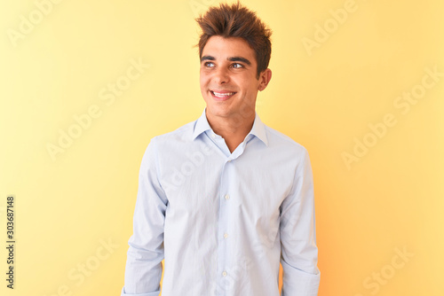 Young handsome businessman wearing elegant shirt over isolated yellow background smiling looking to the side and staring away thinking.