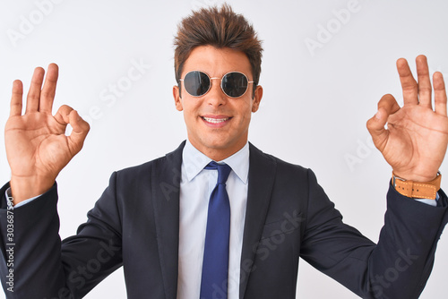 Young handsome businessman wearing suit and sunglasses over isolated white background relax and smiling with eyes closed doing meditation gesture with fingers. Yoga concept.