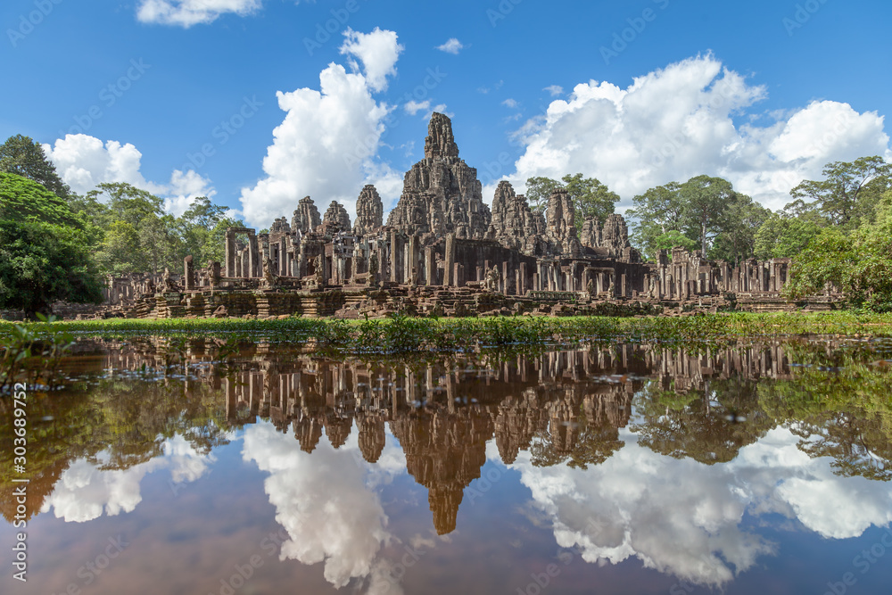 Bayon temple and its perfect clear reflection in the water. Impressive clouds and a blue sky compliment the scene. Bayon g