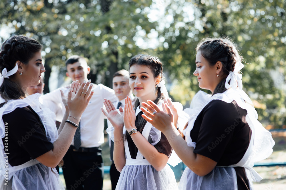 Obraz premium Three girls schoolgirls girlfriends, teenagers laugh rejoice. Rest after lessons school college. Three girls in school uniform. Back to school. Happy girls relax after school emotions joy delight