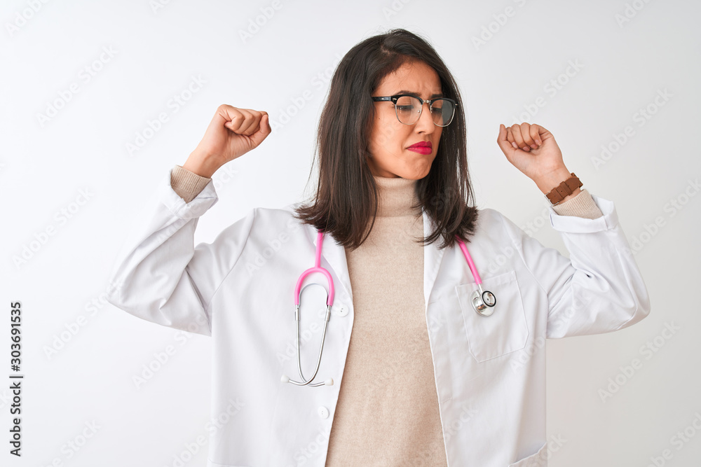 Chinese doctor woman wearing coat and pink stethoscope over isolated white background showing arms muscles smiling proud. Fitness concept. Chinese doctor woman wearing coat and pink stethoscope over isolated white background showing arms muscles smiling proud. Fitness concept.