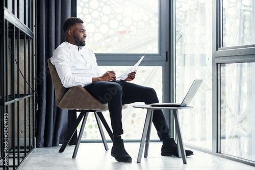 фотографія Handsome afro american businessman working at the laptop and analysis in the specially designated room in modern stylish office
