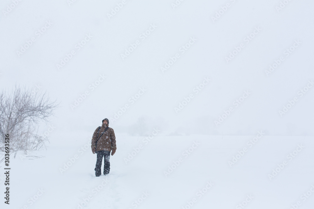 A village man walks in the winter in the field. Snow blizzard