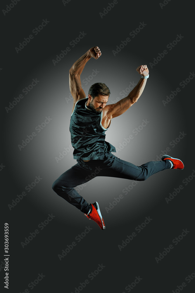joyful athletic build man jumping on air on a black background. Lifestyle and sport concept