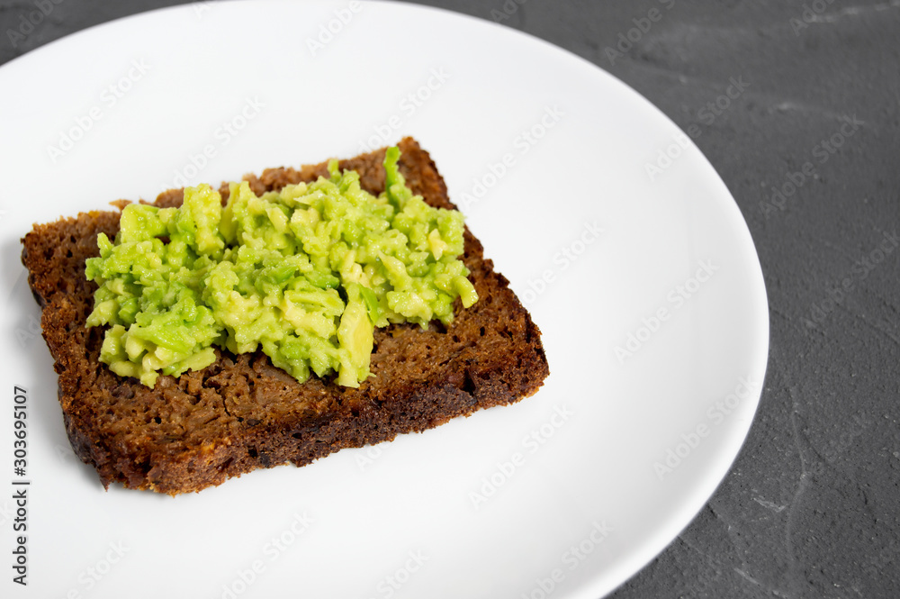 Rustic toast with smash avocado and cereal bread on plate and concrete Rustic toast with smash avocado and cereal bread on plate and concrete
