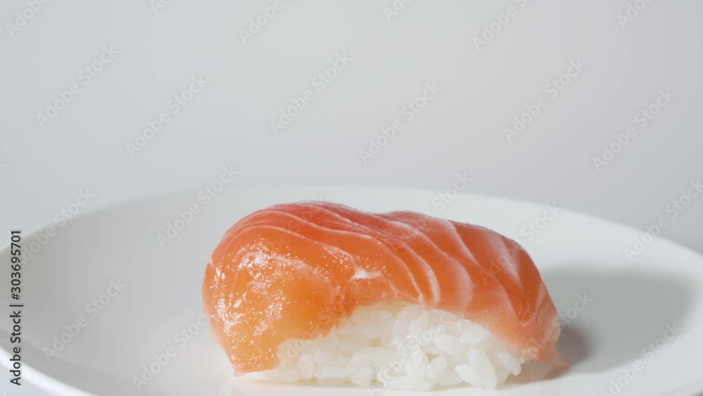 Putting Japanese Salmon Sushi on Plate with Chopsticks Putting Japanese Salmon Sushi on Plate with Chopsticks