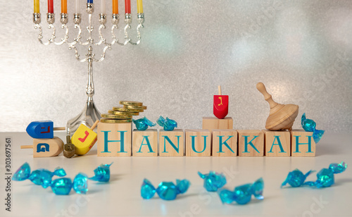 concept of of jewish religious holiday hanukkah with hanukkah chandellier (menorah) wooden spinning top toys (dreidel), cubes saying 