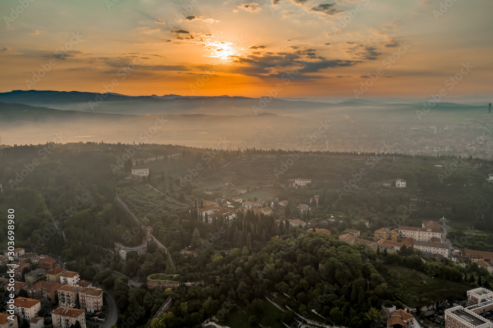 Aerial drone shot view of sunrise on foggy Veronetta colline with Castel San Pietro and funicolare
