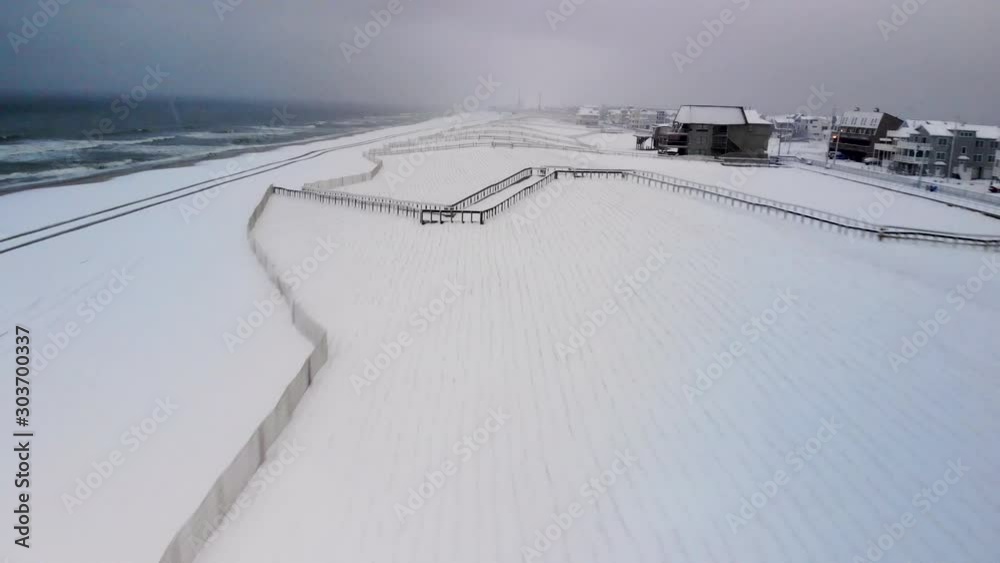Aerial moving over freshly snow covered dunes in a beach town during a snow storm. Aerial moving over freshly snow covered dunes in a beach town during a snow storm.
