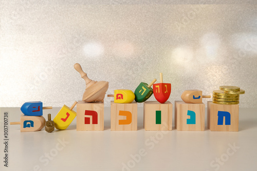 concept of of jewish religious holiday hanukkah with wooden spinning top toy (dreidel), wooden cubes saying 