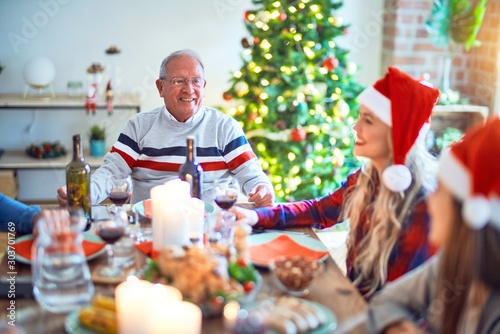 Beautiful family wearing santa claus hat meeting smiling happy and confident. Eating roasted turkey celebrating Christmas at home
