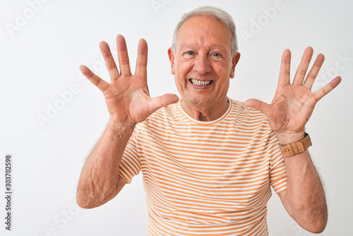 Senior grey-haired man wearing striped t-shirt standing over isolated white background showing and pointing up with fingers number ten while smiling confident and happy.