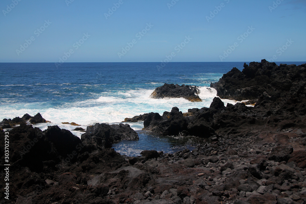 The intense blue sea and the black volcanic rocks